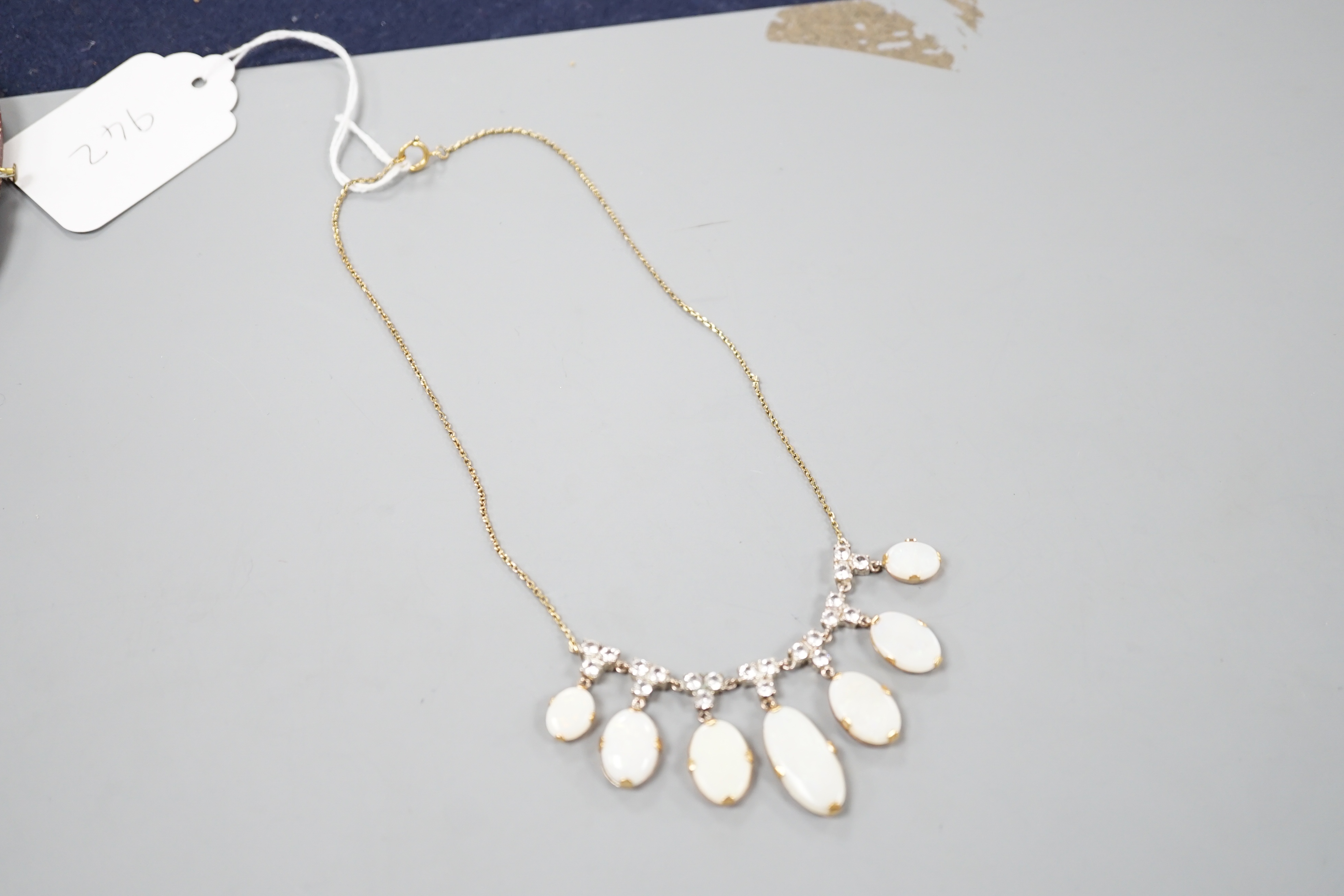 A yellow metal, graduated seven stone oval white opal and paste set cluster fringe necklace, 42cm, gross 14.6 grams.